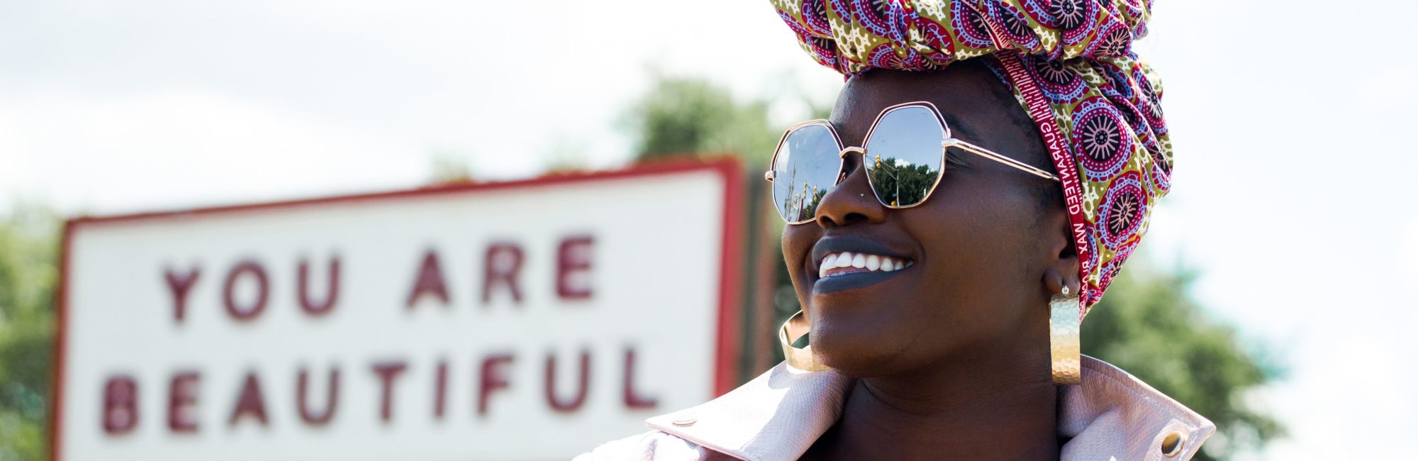 Woman in front of sign that says "YOU ARE BEAUTIFUL"